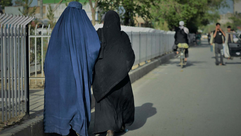 Women wearing a burqa (L) and a Niqab (R) walk along a street in Kabul on May 7, 2022