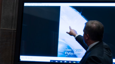 bărbat arată cu degetul spre un ecran pe care rulează un clip video