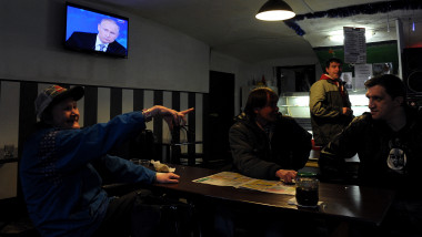 Ruși într-un bar de votcă, ascultă discursul lui Putin