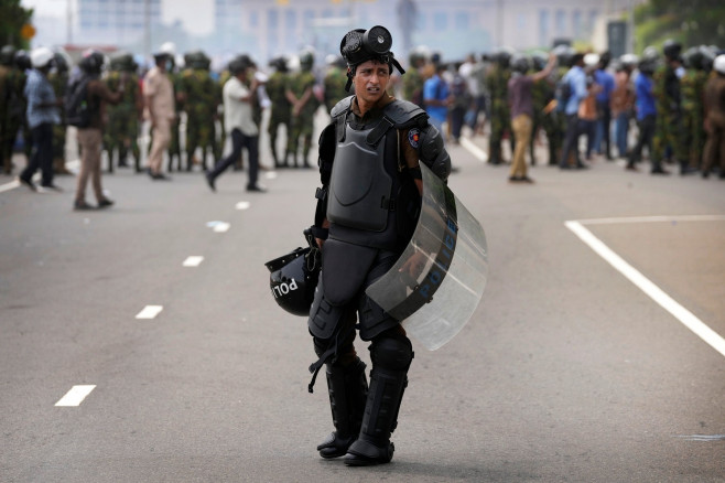 polițist singur cu scut în fața unei mulțimi de protestatari