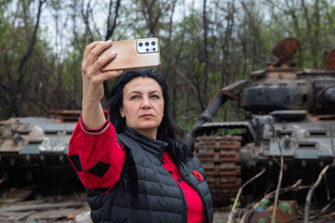 Makariv village, Kyiv region, Ukraine. 7th May, 2022. A woman takes a selfie in front of a destroyed Russian tank. Destroyed and burned tanks of the Russian invaders near Makariv village, Kyiv region, Ukraine, May 7, 2022. Russia invaded Ukraine on 24 Fe