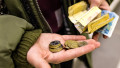băiat care ține în mâini mai multe monede și bancnote de grivne ucrainene