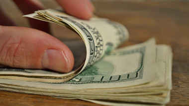 Male hand checking and counting heap of American Dollars