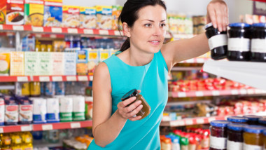 Woman choosing jar of fruit jam
