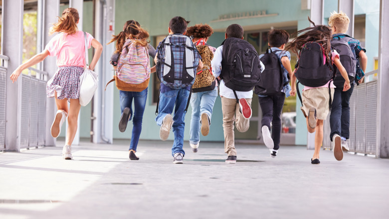 Group of elementary school kids running at school, back view