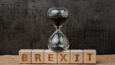 Brexit, time countdown for the UK to deal and withdraw from Euro zone concept, sandglass or hourglass on wooden cube block with alphabet building the word BREXIT on wood table, dark black background