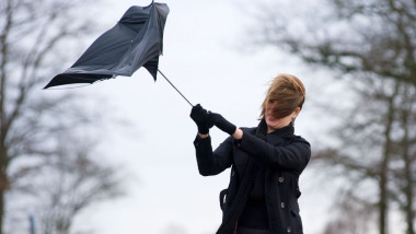 o femeie tine umbrela luata de vant.
