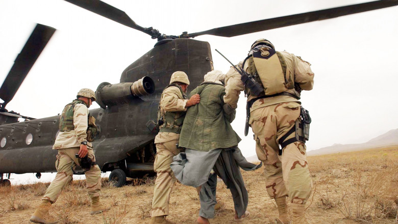 un afgan este dus de maini de doia soldati din trupele speciale americane catre un elicopter