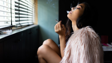 Fată sexy fumează, inhalează fum dintr-o țigară