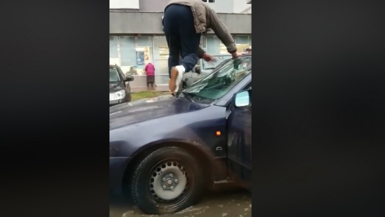Un barbat isi escaladeaza masina pentru a evita baltile