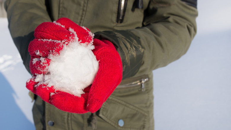 hands in red gloves holding snowball