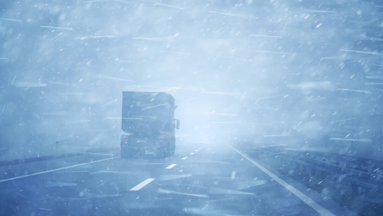 Concept truck vehicle at highway road during a heavy snowfall and rainfall.