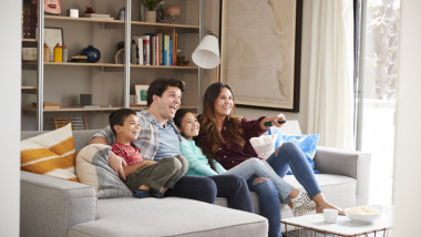 Family Relaxing On Sofa At Home Watching Television