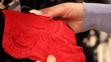 Woman chooses red lace panties hanging on rack in lingerie store, spring collection