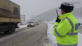 un politist dirijeaza un drum national pe timp de ninsoare.