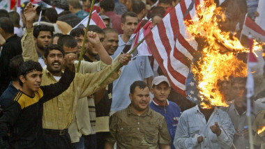 Susținători ai clericului șiit Moqtada al-Sadr dau foc steagului SUA într-o manifestație la Bagdad, în 2009