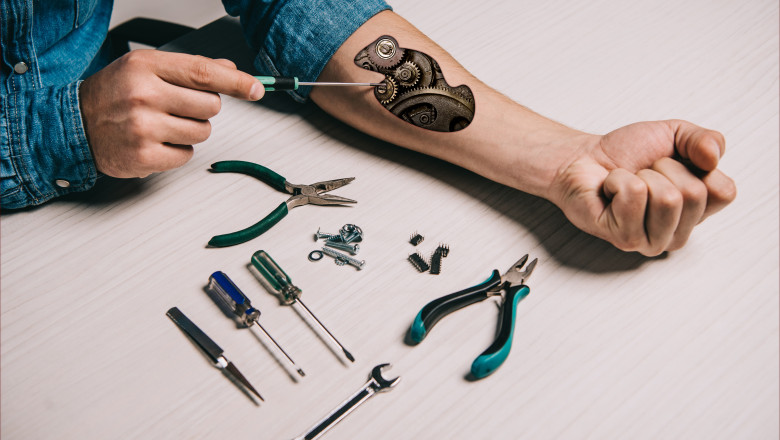 cropped view of man repairing metallic mechanism in arm with screwdriver