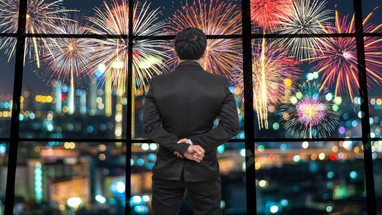 Back side of Businessman looking at Fantastic fireworks on the photo blurred of cityscape at night scene background,Business and holiday concept