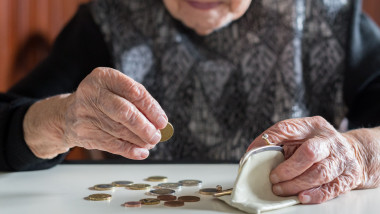 Elderly woman sitting at the table counting money in her wallet.
