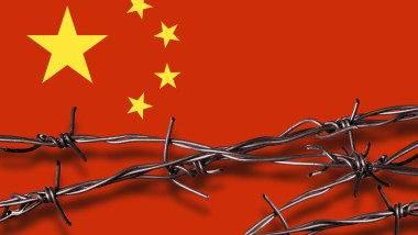 Barbed wire with shadow in front of a Chinese flag