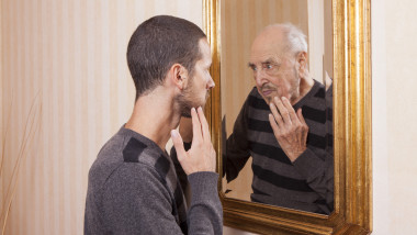 young man looking at an older himself in the mirror