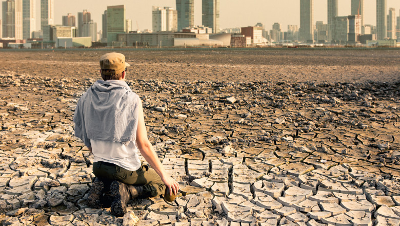 A man in the desert looks at the city after the effects of global warming