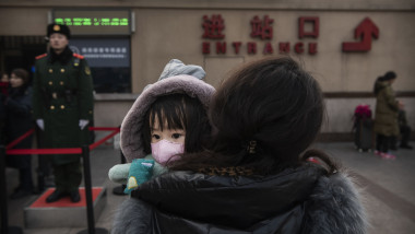 BEIJING, CHINA - JANUARY 21: A Chinese girl wears a protective mask as she is held by a relative as they wait to board a train at Beijing Railway station before the annual Spring Festival on January 21, 2020 in Beijing, China. The number of cases of a deadly new coronavirus rose to nearly 300 in mainland China Tuesday as health officials stepped up efforts to contain the spread of the pneumonia-like disease which medicals experts confirmed can be passed from human to human. The number of those who have died from the virus in China climbed to six on Tuesday and cases have been reported in other parts of Asia including in Thailand, Japan, Taiwan and South Korea. (Photo by Kevin Frayer/Getty Images)