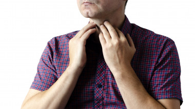 Closeup view of a young male with a sore throat or pain on the neck or thyroid. The concept of body problems of people