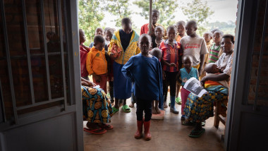 multi copii africani asteapta la intrarea intr-o casa
