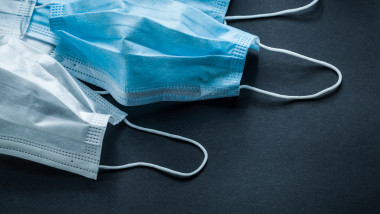 Disposable sterile masks on black background medicine concept