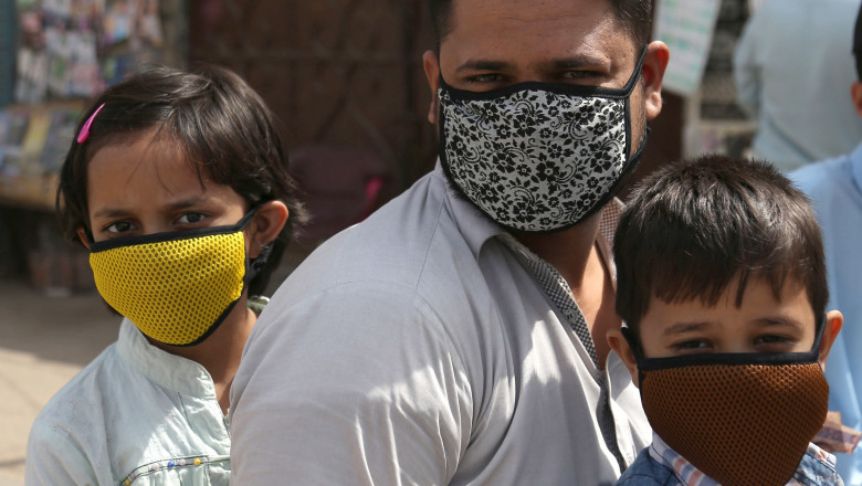Un barbat si cei doi copii ai sai poarta masti pentru a se feri de coronavirus, in Iran