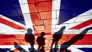 Conceptual shadows of group of people walking through the streets with painted United Kingdom flag on the floor.