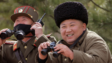 Kim Jong Un, cu o căciulă de blană pe cap, zâmbește în timp ce asistă la un exercițiu miliitar al armatei Coreii de Nord