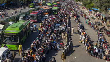 GHAZIABAD, INDIA - MARCH 28: Crowds of Indian migrant workers wait to board buses to return to their native villages as a nationwide lockdown continues in an attempt to stop the spread of coronavirus (COVID-19) on March 28, 2020 in Ghaziabad, on the outskirts New Delhi, India. India is under a 21-day lockdown to fight the spread of the virus while security personnel on the roads are enforcing the restrictions in many cases by using force, the workers of country's unorganized sector are bearing the brunt of the curfew-like situation. The lockdown has already disproportionately hurt marginalized communities due to loss of livelihood and lack of food, shelter, health, and other basic needs. The lockdown has left tens of thousands of out-of-work migrant workers stranded, with rail and bus services shut down. According to international labour organisations 90 percent of India's workforce is employed in the informal sector and most do not have access to pensions, sick leave, paid leave or any kind of insurance. The closing of state borders have caused disruption in the supply of essential goods, leading to inflation and fear of shortages. Reports on Thursday said that Prime Minister Narendra Modi's government is preparing a massive bailout for the underprivileged sections of the country and will hand over the aid through direct cash transfers. (Photo by Yawar Nazir/Getty Images)