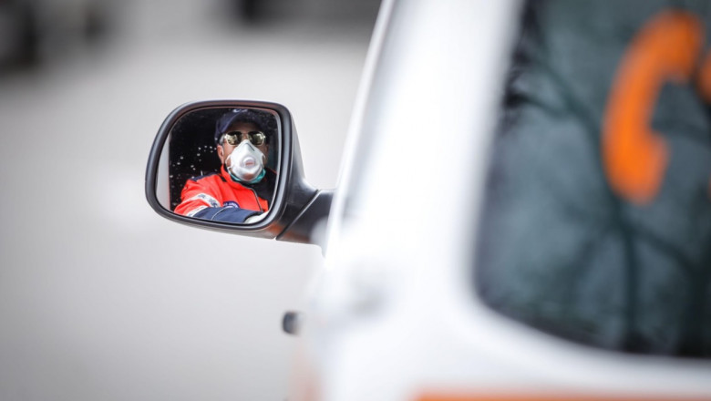 Bucharest, Romania - April 1, 2020: Ambulance driver seen in the side mirror of the vehicle.