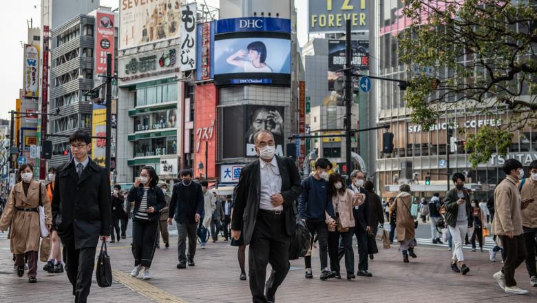 oameni cu măști pe fețe merg pe stradă în Japonia în timpul pandemiei de coronavirus
