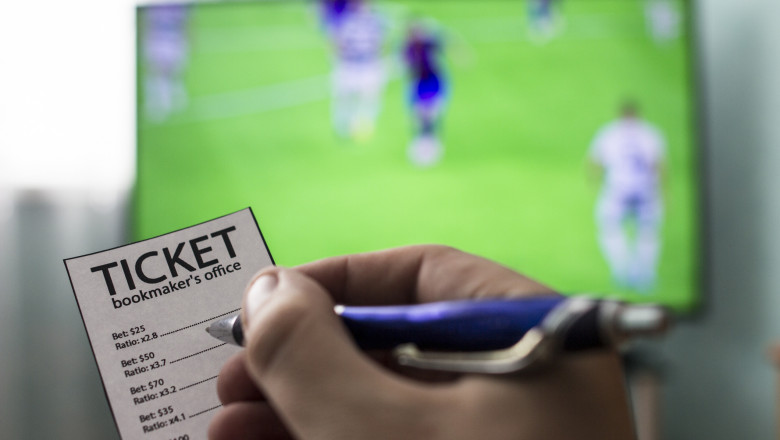Men's hands with a ticket bookmaker's office, on TV show football, Champions League, sports betting, close-ups