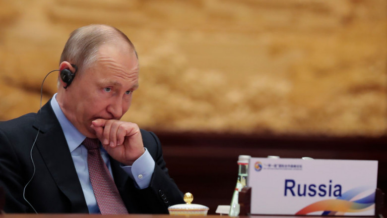 preşedintele Rusiei, Vladimir Putin, cu o casă pe cap, ascultă