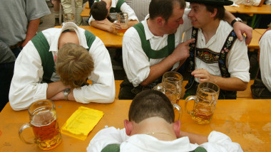 MUNICH, GERMANY - SEPTEMBER 21: Two drunken men in traditional Bavarian outfits converse beside their passed out comrades at the annual Oktoberfest celebration September 21, 2003 in Munich, Germany. The 170th Oktoberfest runs from September 20 through October 5 and organizers are expecting 6 million visitors. (Photo by Sean Gallup/Getty Images)