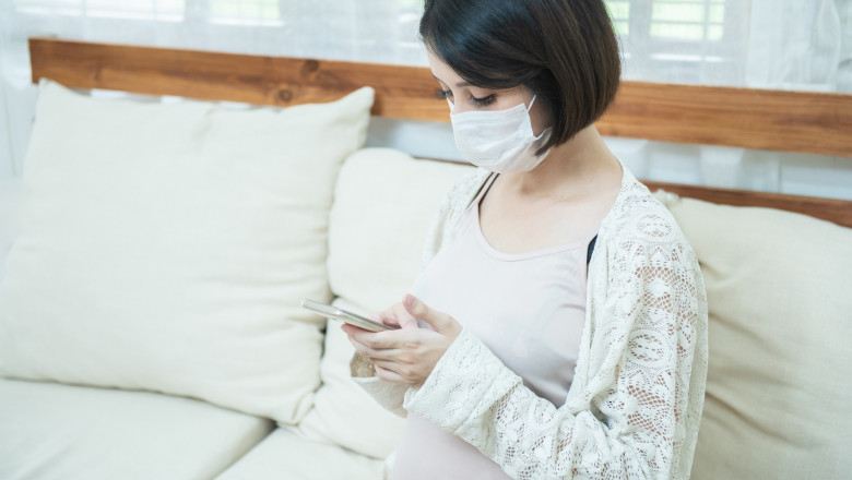 GettyImages-femeie însărcinată uitându-se pe telefon
