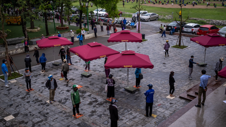 Oameni respectând distanțarea socială și stând la coadă pentru orezul gratis furnizat de guvernul din Vietnam