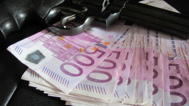 pistol pus pe un teanc de bancnote de 500 de euro