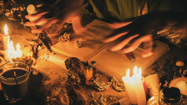 Hands fortune teller over an ancient table with herbs and books. Manifestation of occultism in the form of divination