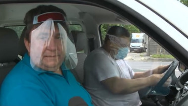 Instructorul auto și elevul sunt despărțiți în mașină de o folie transparentă și flexibilă din plastic