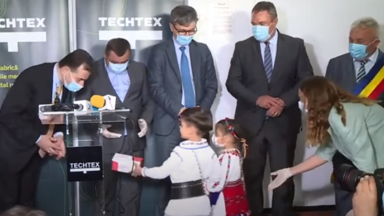 Premierul Ludovic Orban primește o cutie cu măști de la doi copii, la o fabrică din Târgu Lăpuș