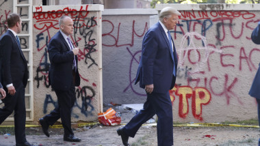 Donald Trump trece pe lângă un zid pe care protestatarii au scris cu graffiti, în timp ce merge pe jos de la Casa Albă la biserica St. John