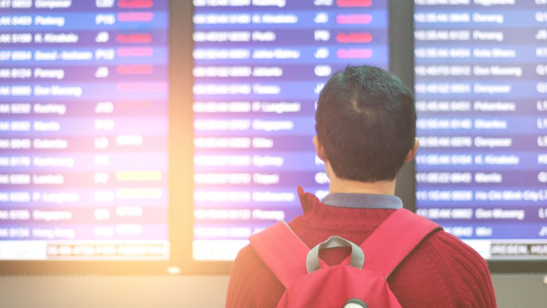 un barbat priveste pe un aeroport tabelul avioanelor anulate din cauza restrictiilor de calatorie