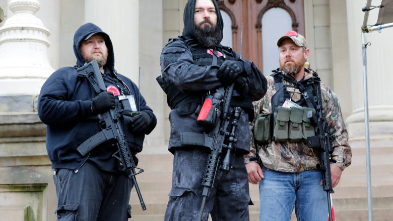 (FILES) In this file photo taken on April 30, 2020, armed protesters provide security as demonstrators take part in an "American Patriot Rally," organized by Michigan United for Liberty on the steps of the Michigan State Capitol in Lansing, demanding the reopening of businesses. A far-right movement whose followers have appeared heavily armed at recent US protests has suddenly become one of the biggest worries of law enforcement, after one killed two California police officers.,Image: 532773727, License: Rights-managed, Restrictions: TO GO WITH AFP STORY by W.G. DUNLOP, "Debate on reopening US plays out online and in the streets", Model Release: no