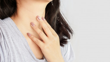 woman hand self checking thyroid gland on her neck