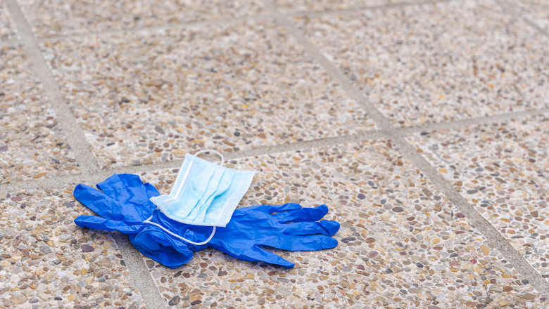 Used nitrile medical gloves and surgical mask lying on the floor